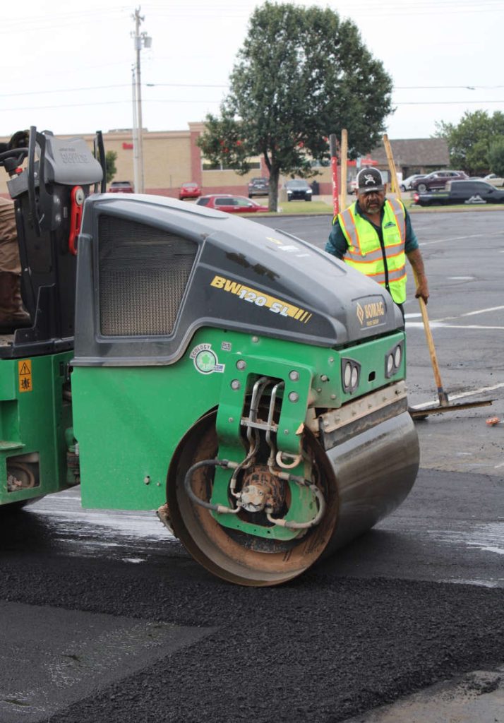 roller compacting asphalt while doing a repair in parking lot.